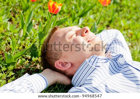Happy man relaxing outdoors lying on grass
