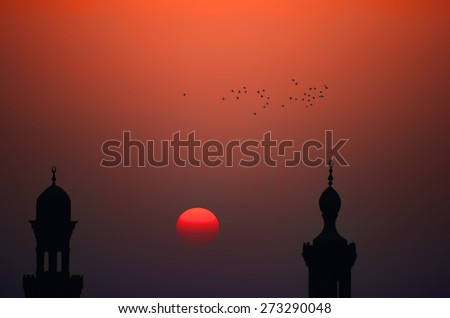 Ibn Tulun Mosque minaret silhouettes at sunset, evening Sun, flock of birds, Cairo, Egypt