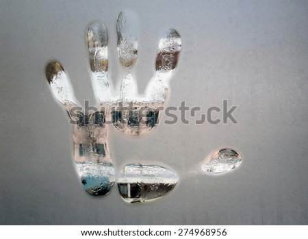 Handprint on a frozen glass, Through the glass part of building is visible