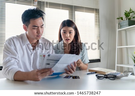 Stressed couple young family husband and wife looking so many expenses bills such as electricity bill,water bill,internet bill,cell phone bill and credit card bill in his hand no money to pay debt