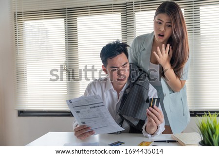 Stressed couple young family husband and wife looking so many expenses bills such as electricity bill,water bill,internet bill,cell phone bill and credit card bill in his hand no money to pay debt Photo stock © 