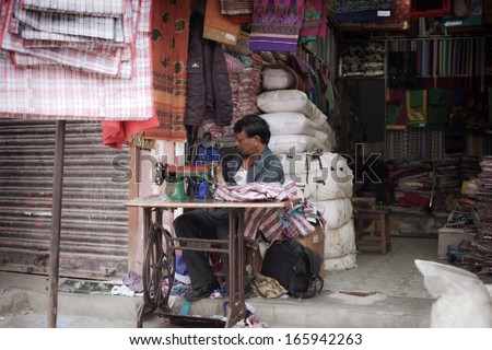 KATHMANDU - OCTOBER 2: man sewing in a small tailor shop, industrial sewing machine in l Kathmandu on October 2, 2013 in Kathmandu, Nepal.