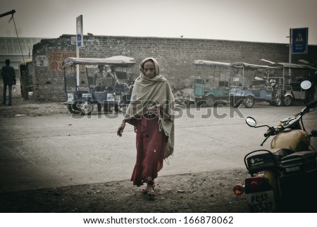 DELHI, INDIA - NOVEMBER 10: Morning on a street , poor woman with roti, at November 10, 2013 in Old Delhi, India.