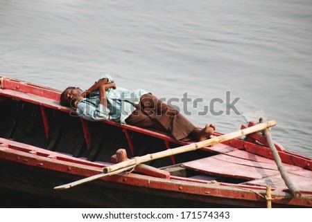 VARANASI, INDIA - NOVEMBER 22: A lot of people sit on the crowded boats to cross the Ganges River on November 22, 2012 in Varanasi, India. The most holy river of India and Hindu culture.