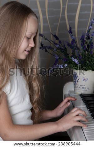 Portrait of little girl in white dress playing piano. Concept of music study and arts