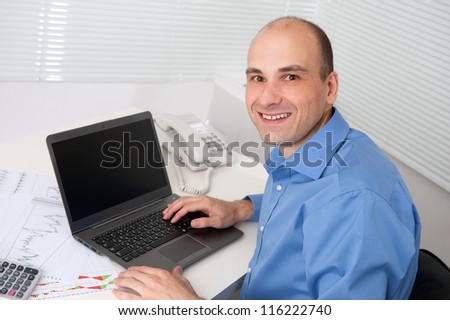 Portrait of relaxed young business man with laptop sitting in office chair