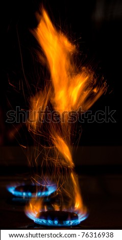 sparks and flames above gas stove burning with blue flames