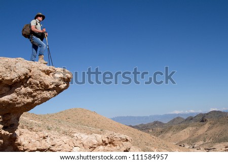 Tourist stands on the brink of a rock and looks in a distance