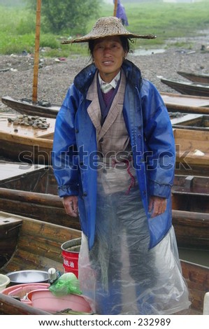 a woman fisher  standing on her boat in a rainy day in Zhejiang China