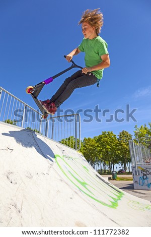 boy jumps with his scooter at the skate park