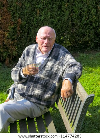 old man enjoys sitting on a bench in his garden