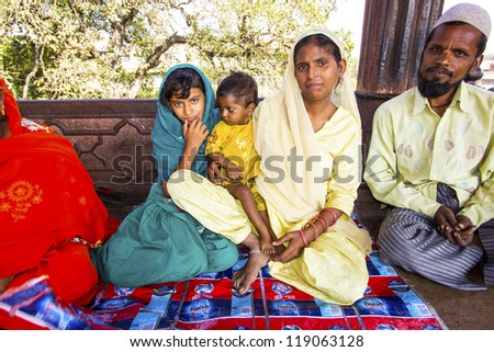 DELHI, INDIA - OCTOBER 16: A family of worshipers rest on the courtyard of Jama Masjid Mosque on October 16, 2012 in Delhi, India. Jama Masjid is the principal mosque of Old Delhi in India.