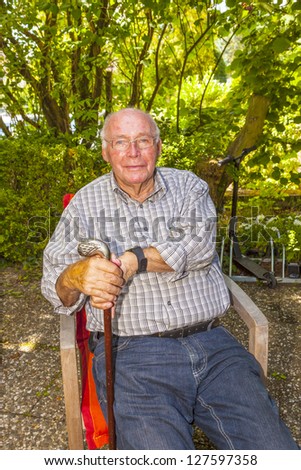 happy laughing senior sitting in his chair in the garden