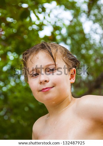 young boy with wet hair comes out of the sea  andsmiling and looks self confident