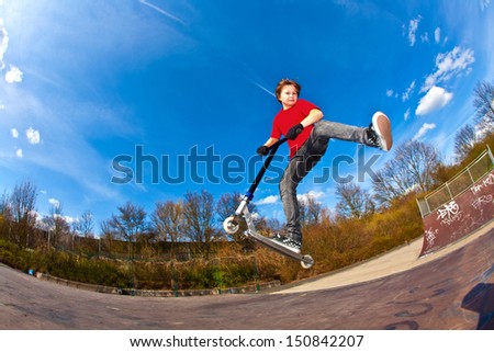 Boy riding a scooter is jumping at a scooter park