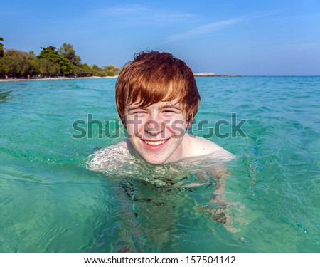 red haired boy enjoys the crystal clear water in the sea
