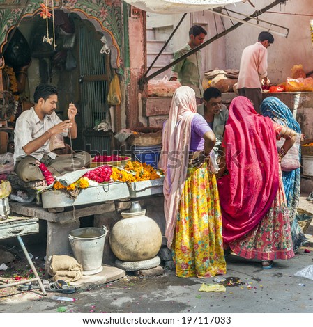 JODHPUR, INDIA - OCTOBER 23, 2012: women buy colorful flowers at the street market in Jodhpur, India. Flower garlands are used for decoration and religious purpose.