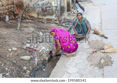 BIKANER, INDIA - OCT 24, 2012: woman tries to find gold dust in the canalization of the gold smith area in Bikaner, India.