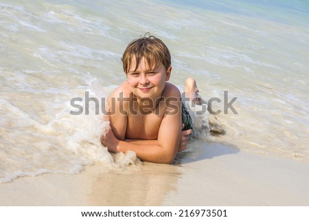 boy is lying at the beach and enjoying the warmness of the water and looking self confident and happy