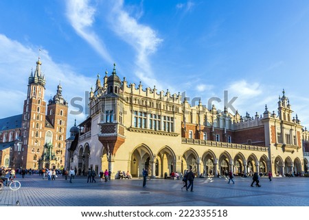 KRAKOW, POLAND - OCT 7, 2014: People on the Main Market Square near Sukiennice, Cloth Hall, and the Town Hall tower. The Cloth Hall was built in XIV century, and now hosts souvenir shops
