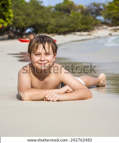 boy iy lying at the beach and enjoying the warmness of the water and looking self confident and happy