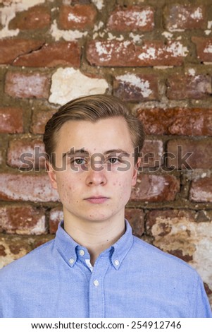 portrait of cute teenage boy in front of grungy brick wall