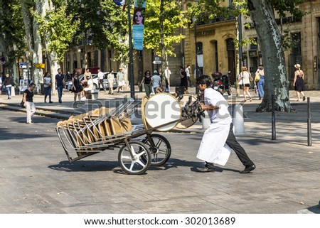 AIX EN PROVENCE, FRANCE - JULY 8, 2015: waiter carries tables for the outdoor restaurant with a sack barrow to the place. in Aix many restaurants serve outdoor dinner.