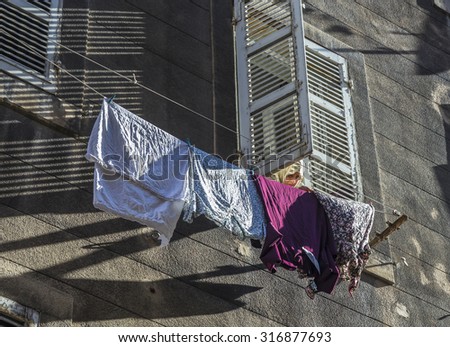 MARSEILLE, FRANCE, JULY 9, 2015: woman with scarf pegs out the washing on a washing line in front of the facade in marseilles, France. Marseille has a high percentage of immigrants due to harbor.