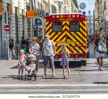 MARSEILLE, FRANCE - JULY 10, 2015: family waits at the sideway to cross the street. An ambulance car with reanimation parks in the pedestrian street.
