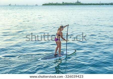 KEY WEST,  USA - AUG 26, 2014: woman enjoys Stand Up Paddle Surfing in Key West. Coastal cultures have stood up within canoes and paddled standing for thousands of years.