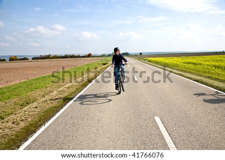 boy on a bicycle ride on a small street in the countryside of Bavaria, Germany in nice landscape