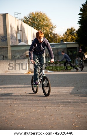 young red haired boy is jumping with his BMX Bike at the skate park with fun