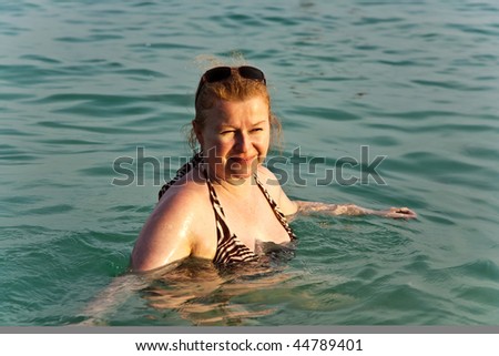 happy woman with red hair enjoys the clear warm salt water in the sea