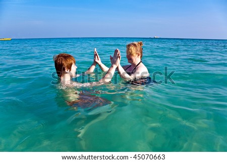 red haired woman and son are enjoying the beautiful clean sea and having fun