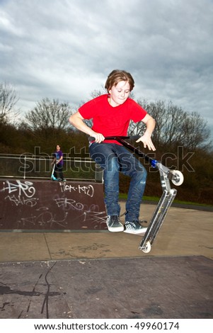 Boy riding a scooter gone airborne on a scooter park