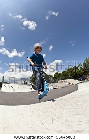 boy has fun with scooter in the skate park