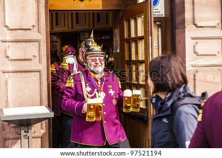 FRANKFURT, GERMANY - MARCH 5: man in carnival uniform gets some beer during the parade on March 5, 2011 in Frankfurt, Germany. Carneval people conquest the town hall and get the key for one day.
