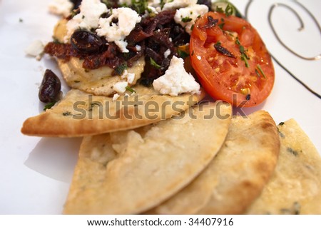 Plate of pasta with tomato, olives, bread and feta cheese