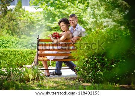 Love story of happy couple. Groom and Bride sitting on a bench in a park. wedding dress. Bridal wedding bouquet of flowers. feelings, relations, passion