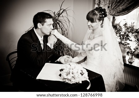 Happy young bride and groom sitting at a table in a cafe on their wedding day. Wedding couple - new family! wedding dress. Bridal wedding bouquet of flowers