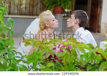 Happy young bride and groom kissing  outside on their wedding day - Copyspace. Wedding couple - new family! wedding dress. Bridal wedding bouquet of flowers