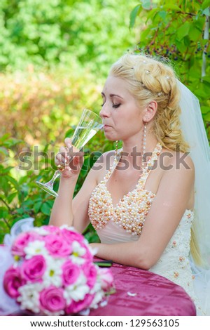 bride holding beautifully decorated wedding glasses with champaign. Happy young bride and groom outside on their wedding day - Copyspace. wedding dress. Bridal wedding bouquet of flowers
