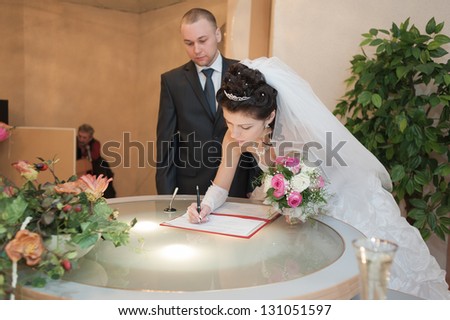 Wedding ceremony. Registry office. A newly-married couple signs the marriage document.Young couple signing wedding documents.