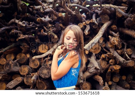 Teen girl in a blue dress in the forest on a background of wood park. fashion portrait of beautiful young female model lady woman  in bright blue dress posing outdoors near bush.