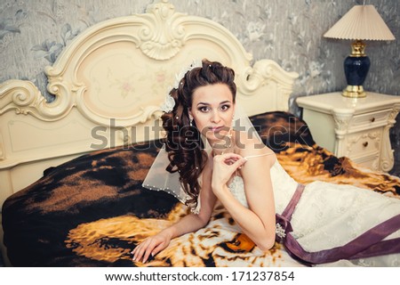 Portrait beautiful bride on bed in wedding day. morning bride. Beautiful bride in white wedding dress lying on the bed in her bedroom.