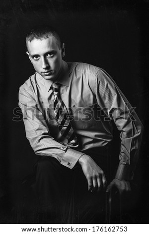 Cool businessman standing on dark gradient background. Picture of a young casual man, over black background.