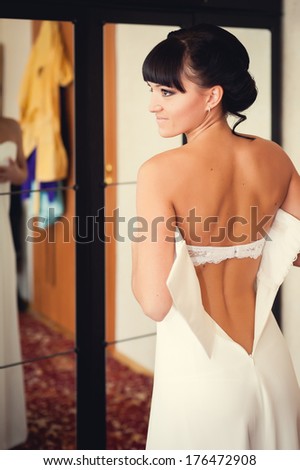 bridesmaid tying bow on wedding dress. beautiful bride in white wedding dress with hairstyle and makeup. Happy sexy girl waiting for groom. Romantic lady have final preparation for wedding