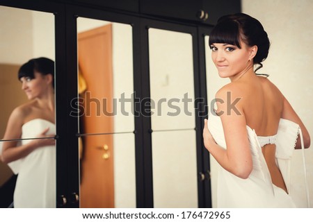 bridesmaid tying bow on wedding dress. beautiful bride in white wedding dress with hairstyle and makeup. Happy sexy girl waiting for groom. Romantic lady have final preparation for wedding
