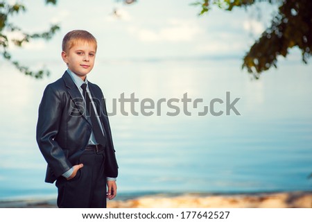 Serious Young boy leaning against tree. Young male teenager smiling in the afternoon in the park.