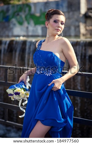Beautiful woman in blue dress with bouquet of flowers posing outdoor. bride in blue dress with bouquet of flowers